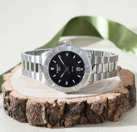 Steel Tissot watch sitting on wooden block