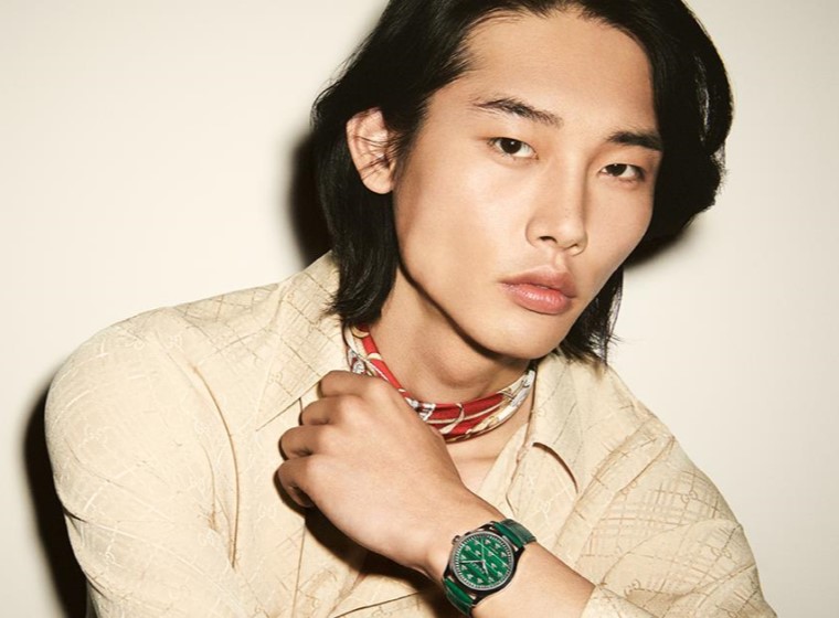 Model in cream top wearing a green Gucci Watch