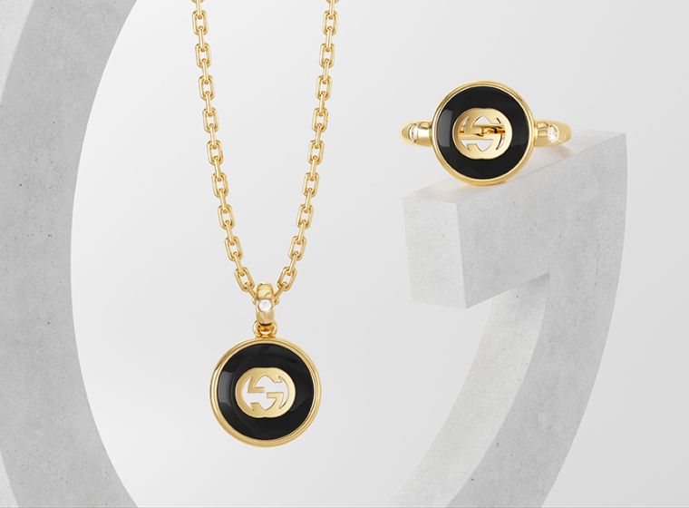 Ladies Gucci Gold & Black necklace and earrings set with white background 