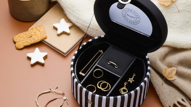 A close up of a jewellery box with 4 gold rings, a gold necklace and 2 gold earrings