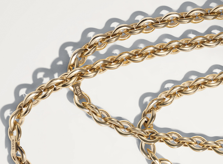 BOSS grey tone curb necklace and bracelet set on a bronze background 