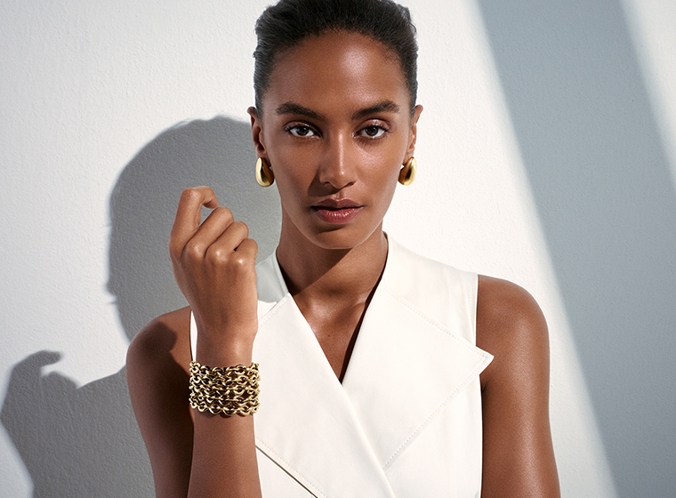 Lady with long light brown hair in a black shirt wearing gold tone BOSS jewellery 