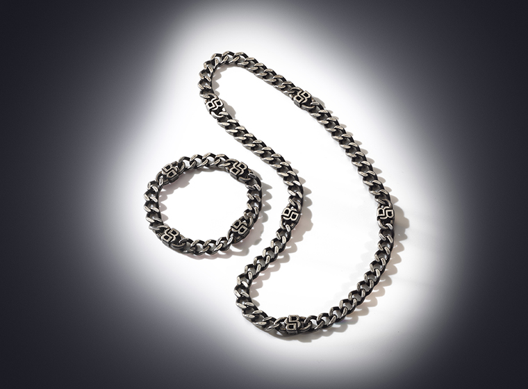 BOSS grey tone curb necklace and bracelet set on a bronze background 