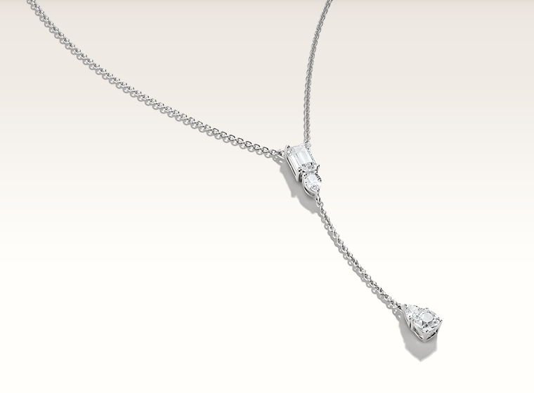 Model wearing a red top holding a gold butterfly necklace near her face