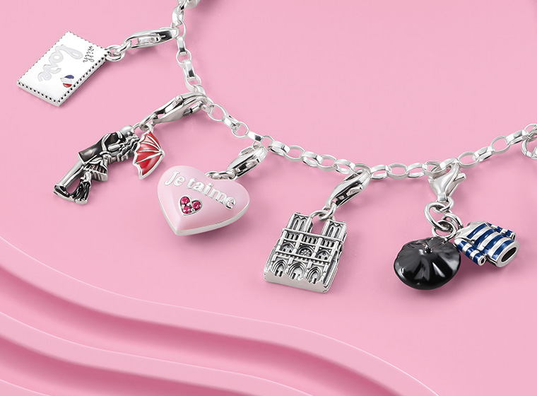 Silver charm bracelet with 5 different coloured charms including a pink heart in the middle 